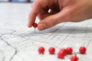 hand putting a pin on map with land and lots