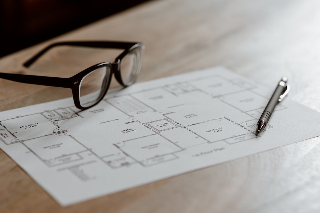 Glasses and pen on architectural drawing plan paper for modular house placed on table