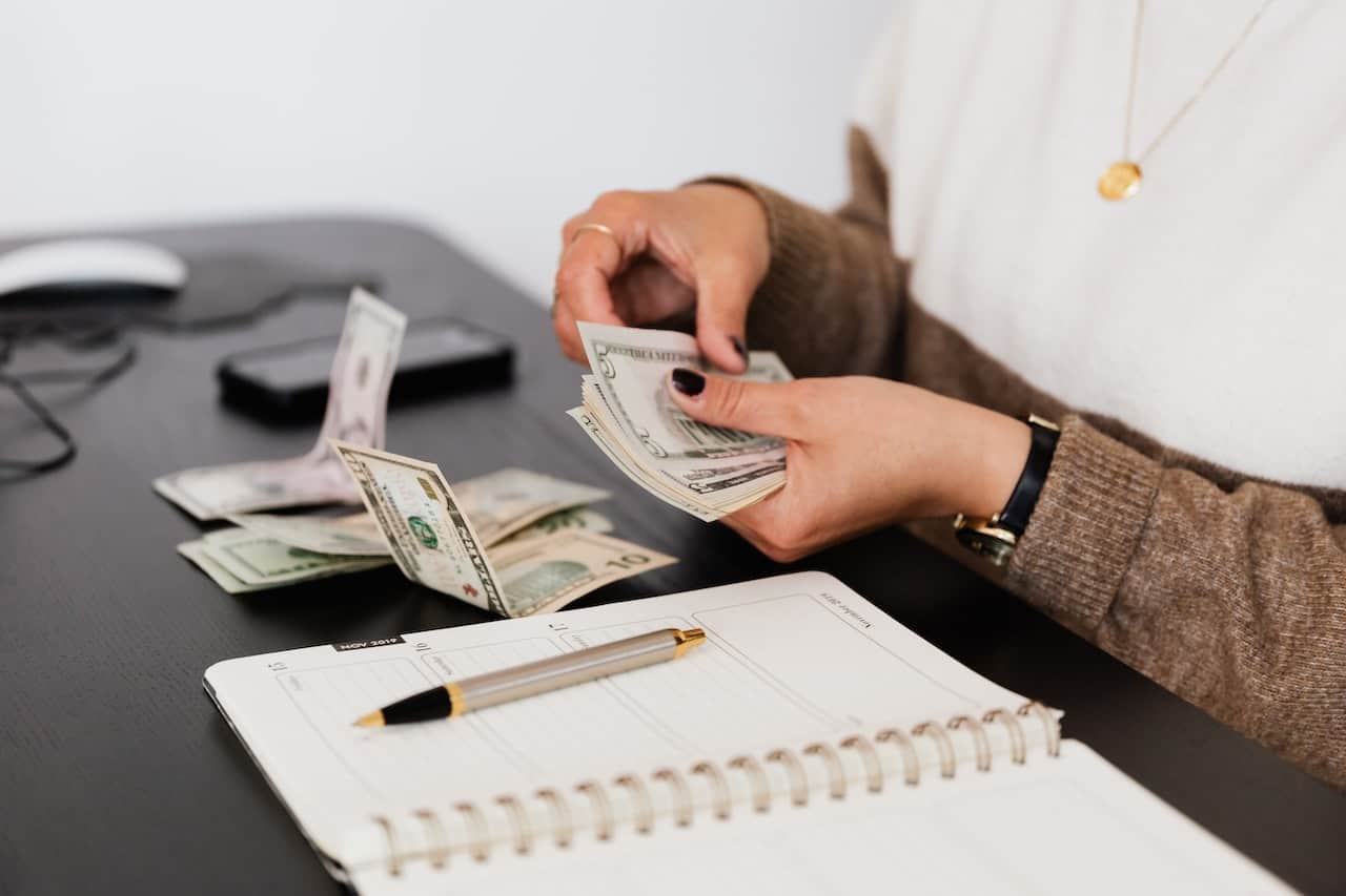 Person counting cash money to buy land