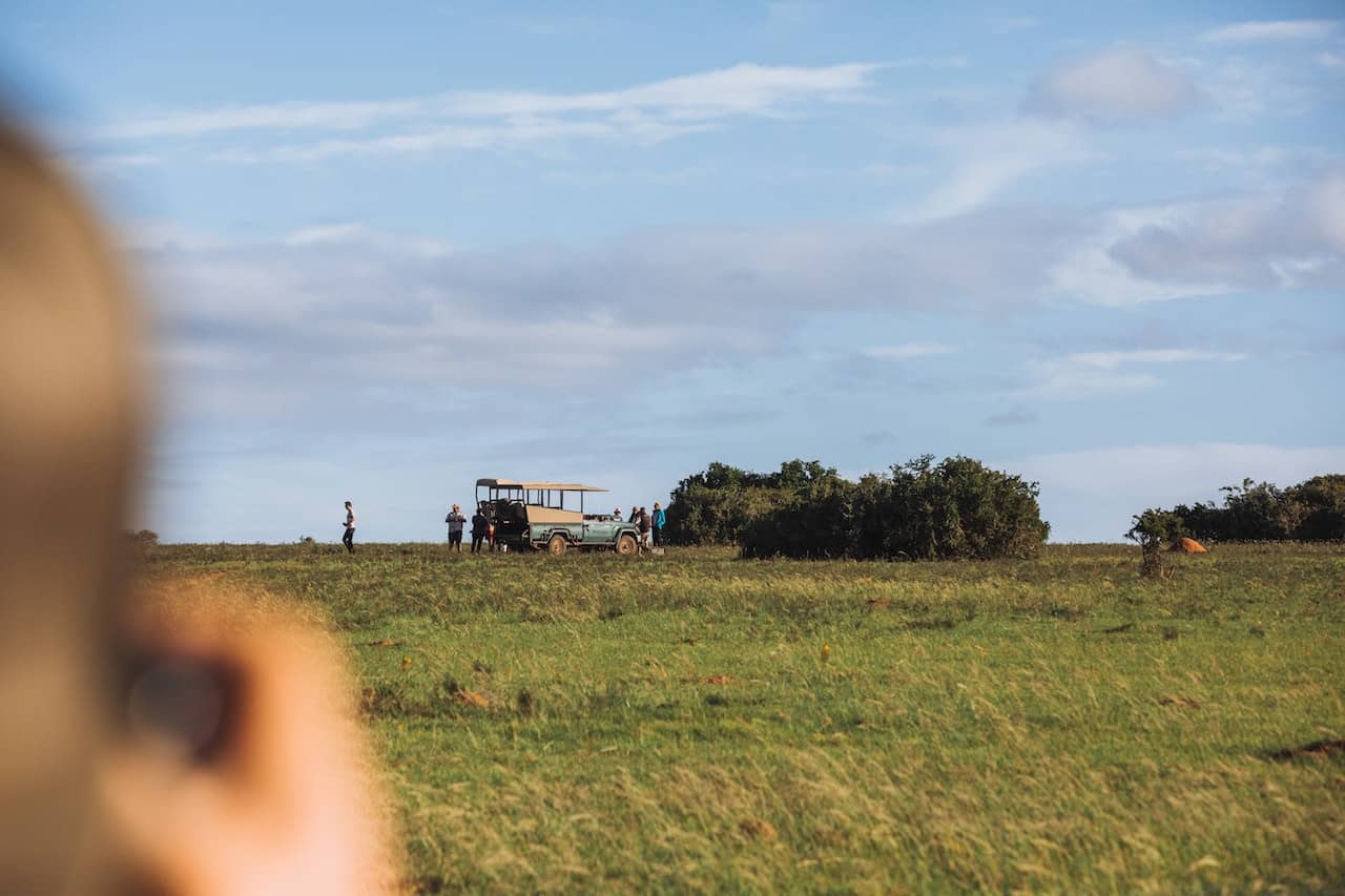 A person taking photo of a safari car parked on a plot of land