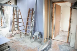 House renovation of a hallway filled with stack of tiles, ladders, rubbed floors and renovation tools