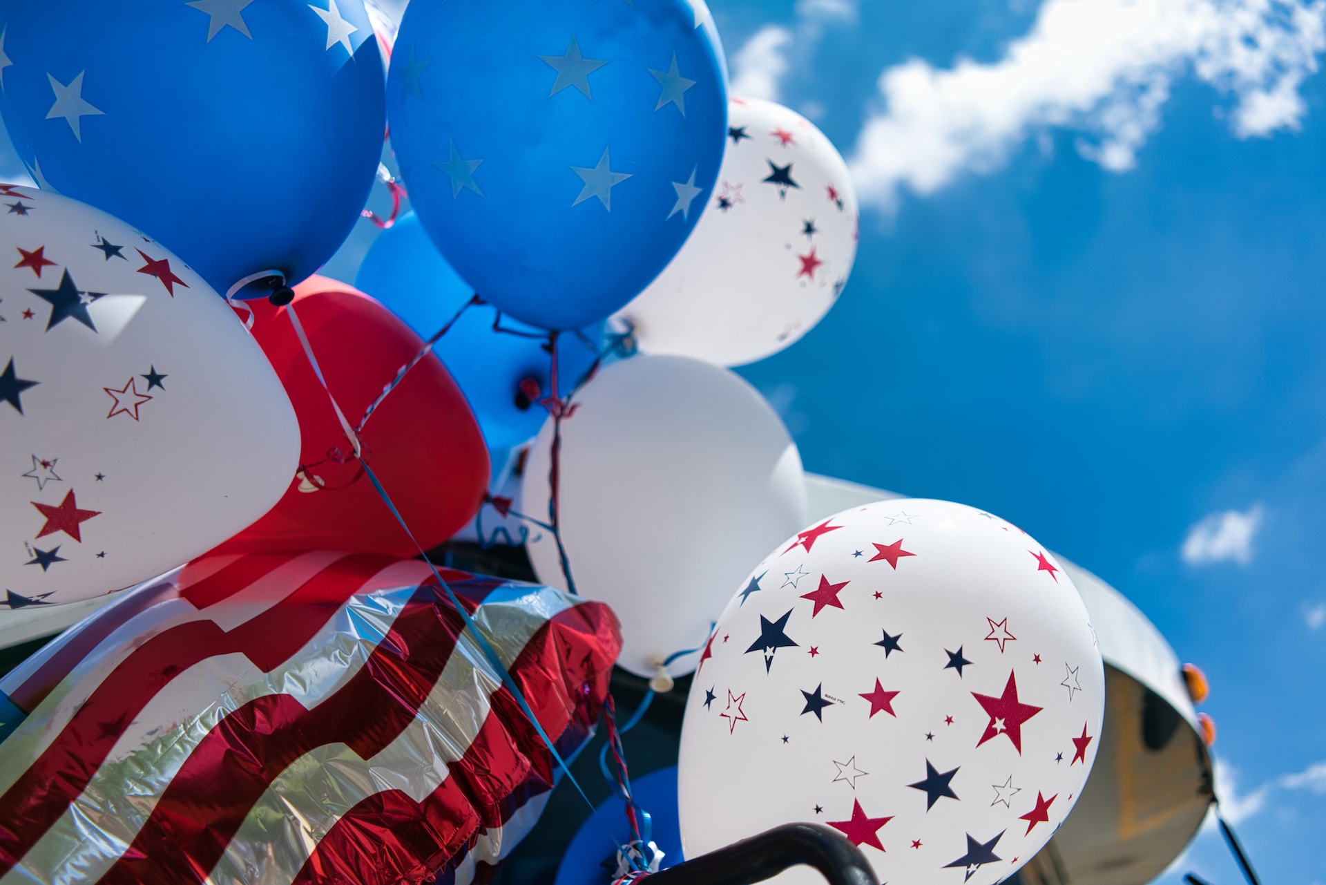 balloons of the American flag and colors waiving on a clear blue sky day for a happy fourth of july
